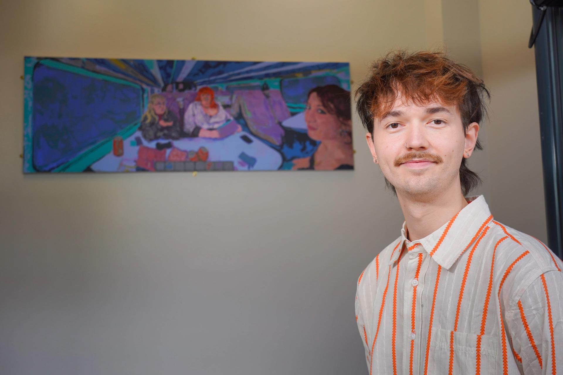 A person with a mustache and striped shirt stands in front of a colorful, abstract painting on the wall, smiling softly. The scene feels artistic and cheerful.